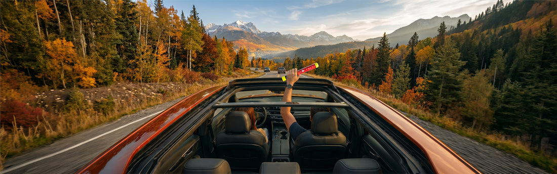 Couple driving on a scenic road with the car's top open and them holding an Element Fire Extinguisher in hand. 